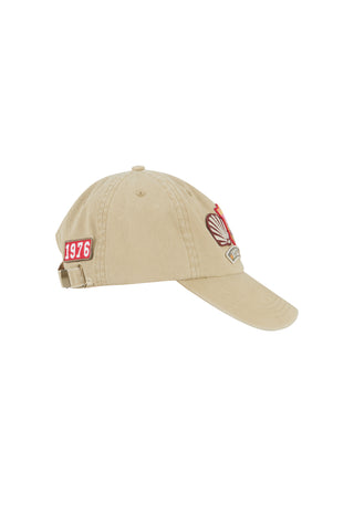 a-beige-baseball-cap-with-a-red-and-white-1976-patch-on-the-side-and-a-red-and-white-crest-patch-on-the-front-shown-against-a-plain-white-background