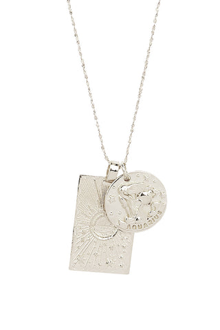 Close up front view of Spell’s Aquarius Stargazer Zodiac Necklace charms. One charm is of a rectangular shape and features a sun with stars while the other charm is circular and features the Zodiac label and icon.